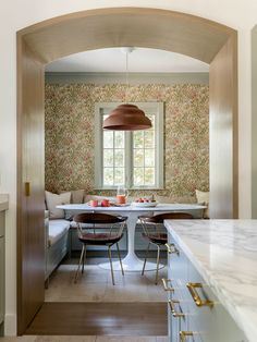 an archway leads to the dining room and breakfast nook, which is decorated in floral wallpaper