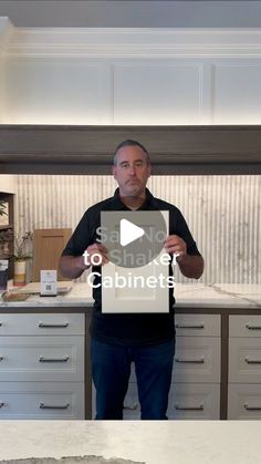 a man standing in front of a kitchen counter holding up a sign with the words how to use cabinets