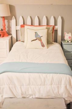 a white bed with a blue and orange pillow on it's headboard next to two nightstands