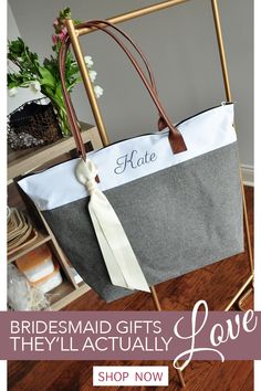 a gray and white tote bag sitting on top of a metal rack next to a potted plant