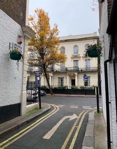 an empty street with white brick buildings and trees on both sides in front of it