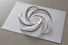 an abstract paper sculpture on top of a piece of white paper with red lines running through it