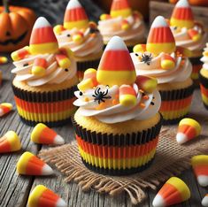 cupcakes decorated with candy corn and witches hats are on a wooden table surrounded by halloween decorations