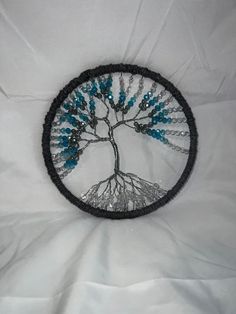 a beaded brooch depicting a tree with blue beads on it's branches