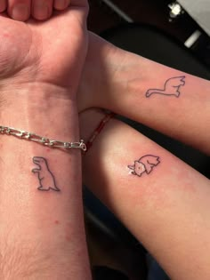 two people holding hands with tattoos on their wrists and wristbands, one has a dog and the other has a cat