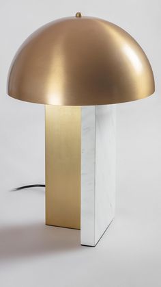 a gold and white table lamp with a black cord