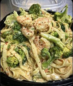 pasta with shrimp, broccoli and sauce in a black bowl on a table