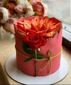 a pink cake with red flowers on top