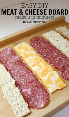 four different types of meat and cheese on a cutting board with crackers in the middle