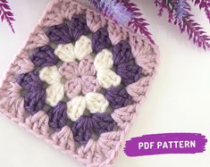 a crocheted square with white and purple flowers