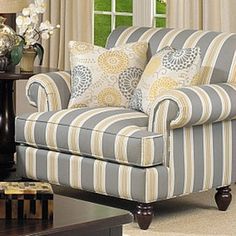 a living room filled with furniture next to a window covered in white and yellow curtains