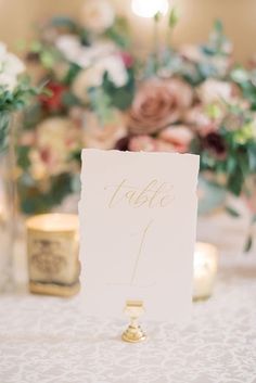 a table with flowers and candles in vases next to a sign that says table 1