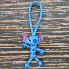 a blue keychain with a small cartoon character on it's side hanging from a wooden surface