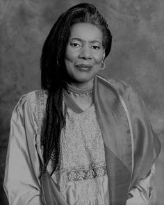 a black and white photo of a woman with dreadlocks on her head wearing a dress