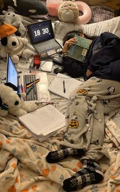 a person is laying in bed with stuffed animals and laptops