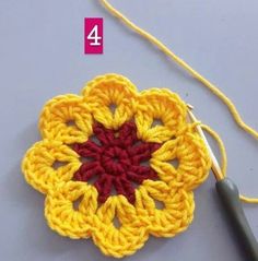 the crochet flower is being worked on by a knitting needle and yarn hook