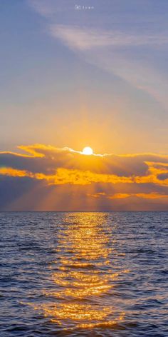 the sun is setting over the ocean with some clouds in the sky and water below