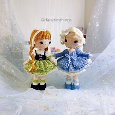 two knitted dolls standing next to each other on a white cloth covered tablecloth