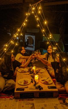 people sitting around a table with food and drinks in front of them at night time