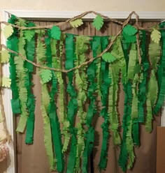 a bunch of green paper leaves hanging from a curtain