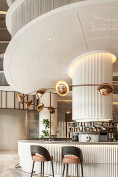 two bar stools in front of a white circular counter with gold lights on it