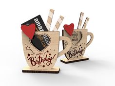 two wooden mugs with hearts and arrows on them, one has a card in the shape of a heart