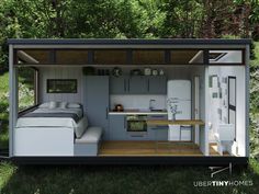 a tiny house with a kitchen and living area in the middle of some grass, surrounded by trees