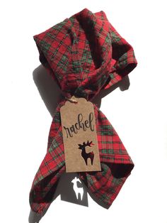 a red and green plaid scarf with a tag that says rachel on the front, sitting on a white surface