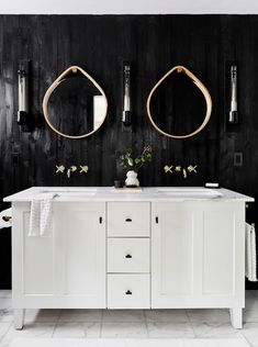 a bathroom with two sinks and mirrors on the wall, along with black wood paneling