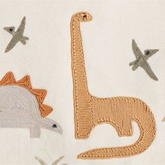 an embroidered fabric with animals and planes on it, including one giraffe in the background