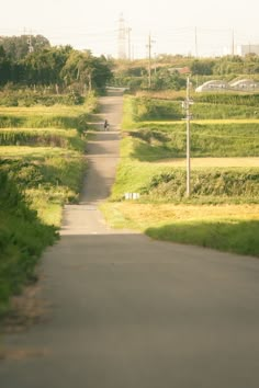 a person riding a motorcycle down a road in the middle of some grass and trees