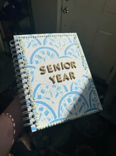 someone is holding up a notebook with the words senior year written in gold on it