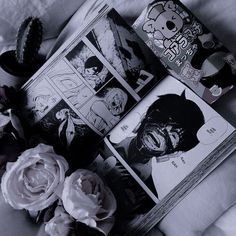 an open book sitting on top of a bed next to flowers and a stuffed animal