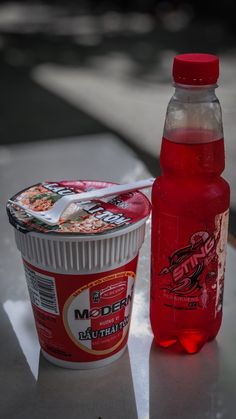 a cup of ice cream next to a bottle of soda