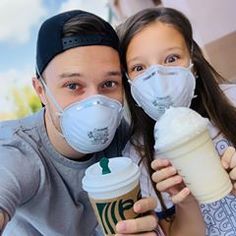 a man and woman wearing face masks holding starbucks cups