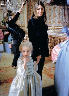 two women standing next to each other in front of a chandelier and dress