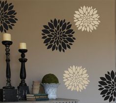 the wall is decorated with black and white flower stencils, candles and books