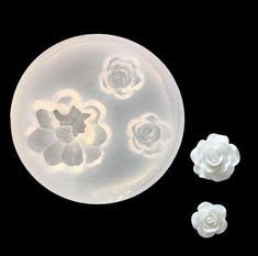 three plastic flowers sitting next to each other on a black surface with one white flower in the middle