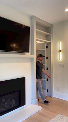 a man standing in front of a fire place next to a tv mounted on a wall