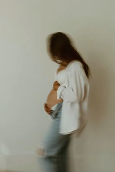 a blurry photo of a woman standing in front of a wall with her stomach exposed