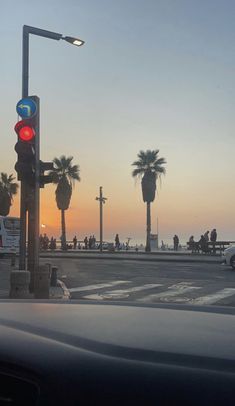 the sun is setting at an intersection with palm trees