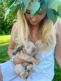 a woman is holding a small bunny in her hands and wearing a wreath on her head