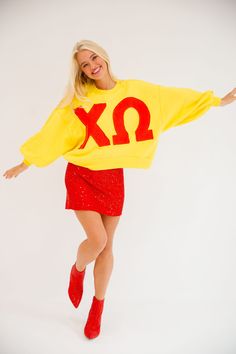 a woman in a yellow sweatshirt and red skirt posing for the camera with her arms outstretched