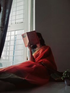 a woman sitting on the floor reading a book