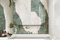 a bath tub sitting next to a white sink in a bathroom with marble walls and floor