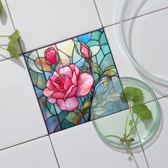 a stained glass rose sits on the floor next to a potted plant