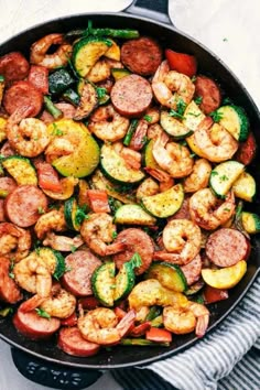 a skillet filled with shrimp, zucchini and other veggies on top of a towel