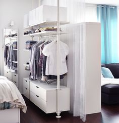 a white closet with clothes hanging on the shelves and other items sitting on top of it