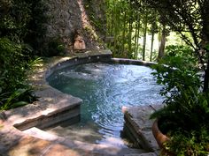 an outdoor hot tub with steps leading up to it and trees in the back ground