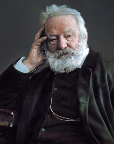 an old man with a white beard is talking on the phone and holding his hand to his ear